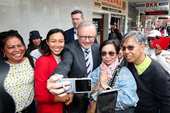 Albanese and Labor candidate for Fowler, Tu Le (in red jacket), take selfies during a shopping centre walk in Cabramatta, Sydney.