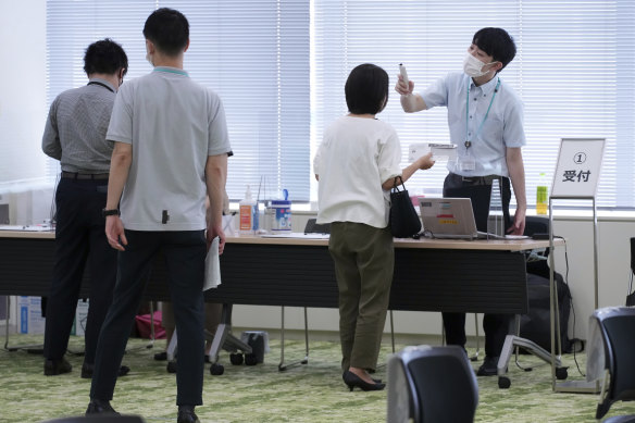 Employees of the beverage maker Suntory register to receive shots of the Moderna COVID-19 vaccine at their office in Tokyo.