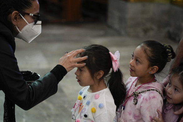 A deaconess marks the forehead of a child with an ash cross at the San Hipolito church in Mexico City.
