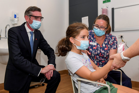 NSW Premier Dominic Perrottet watches on as Ines Panagopailos, 8, receives her first dose of the COVID-19 vaccination at the Sydney Children’s Hospital in Randwick on Monday.