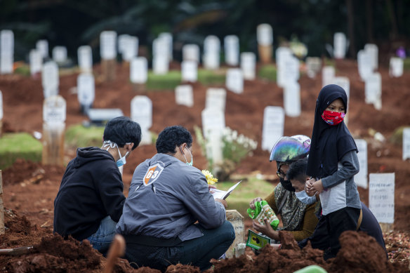 Relatives visit the grave of a COVID-19 victim in Jakarta.