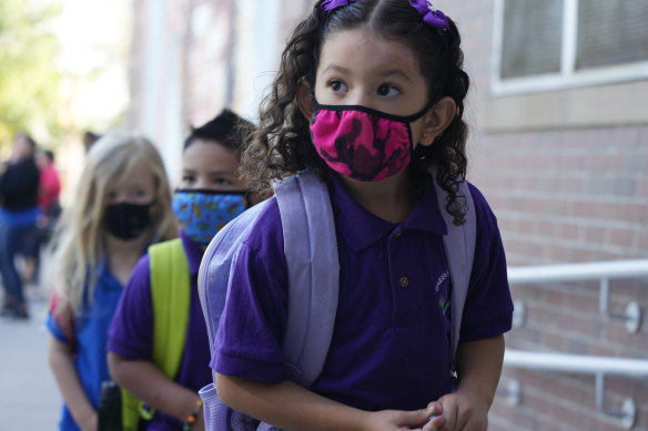 Students wear face coverings as they head into the building for the first day of in-class learning since the start of the pandemic in Denver, Colorado.