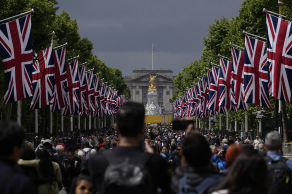 People walk along The Mall looking towards Buckingham Palace, as the road is lined with British flags and closed to traffic for Queen Elizabeth II’s Platinum Jubilee celebrations.