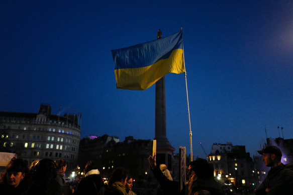A Ukrainian flag is held high during a protest in Trafalgar Square, London.