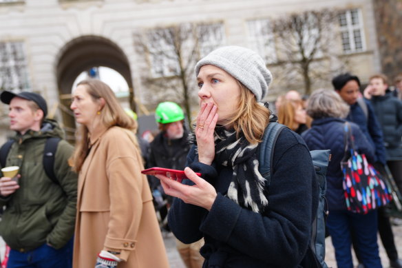 People react to a fire as the Old Stock Exchange building burns in Copenhagen.