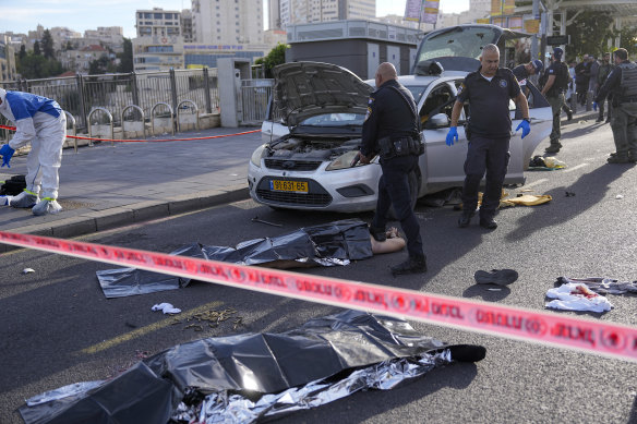 Israeli police officer aims his pistol as rescue workers search the shooting attack site in Jerusalem.