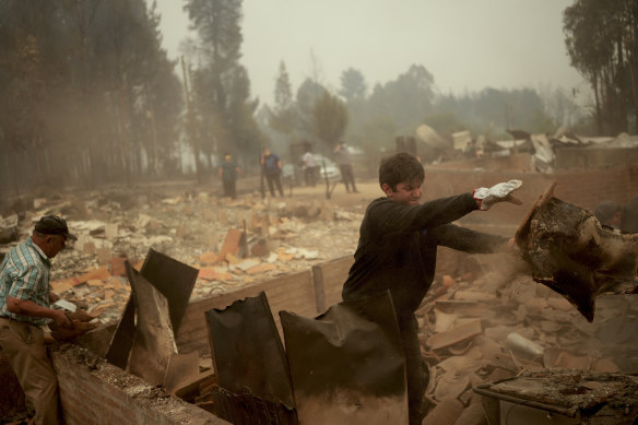 People clear debris after a bushfire swept through the area in Santa Juana, Chile, on Saturday.