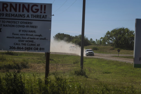 Canadian law enforcement personnel rush to surround a home on the James Smith Cree First Nation reservation in Saskatchewan, Canada.