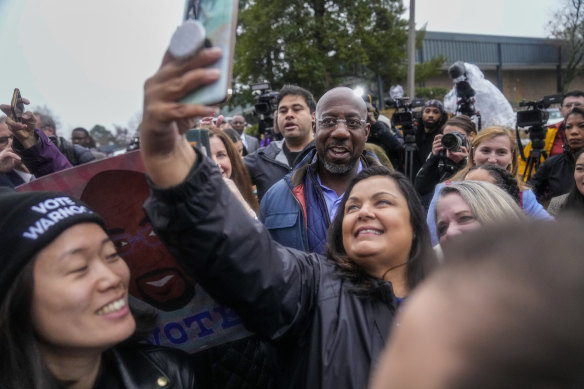 Democratic Senator Raphael Warnock poses with supporters during an election day event in Norcross, Georgia.