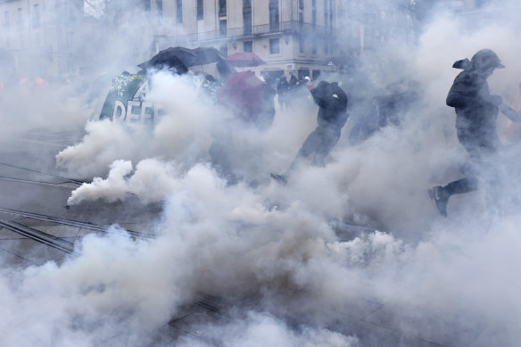 Protesters run through tear gas in Nantes, western France, on Thursday.