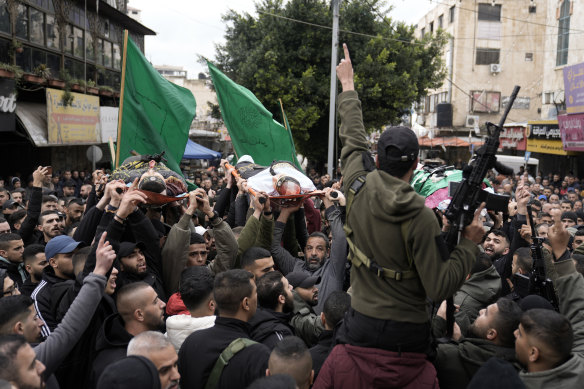 Palestinian gunmen march with bodies of the three militants – draped in the flags of Palestinian Islamic Jihad – killed in the Israeli raid at Ibn Sina Hospital.