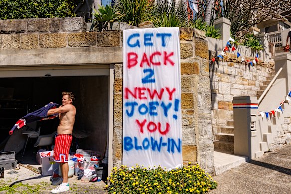Roosters fan Robert Bruns displays a banner taking a lighthearted pop at Andrew Johns at his mum’s property in Bronte.