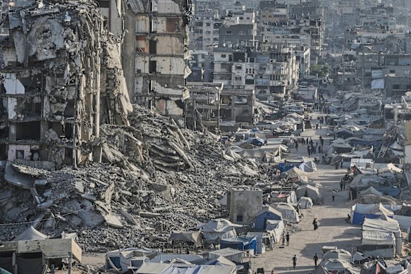 As tendas são cobertas por palestinos, elas parecem ser feridas pela guerra, pelos edifícios do Gaza, a cidade.