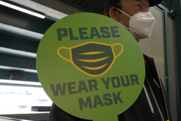 A stadium worker holds up a sign for people to wear face masks before a baseball game in California. 