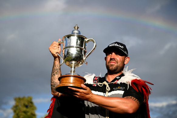 Peake holds the NZ Open trophy as a rainbow fills the sky