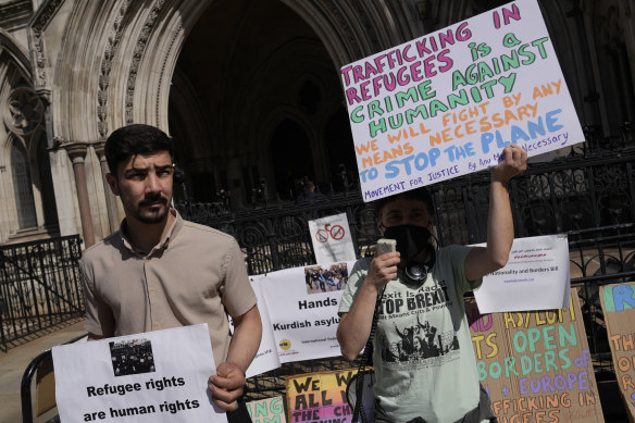 Protesters stand outside the High Court during the hearing on the Rwanda deportation flights in London.