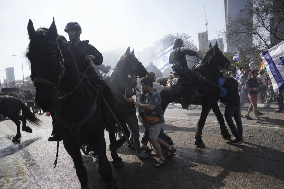 Israeli police deploy horses and stun grenades to disperse Israelis blocking a main road to protest against plans by Prime Minister Benjamin Netanyahu’s new government to overhaul the judicial system, in Tel Aviv.