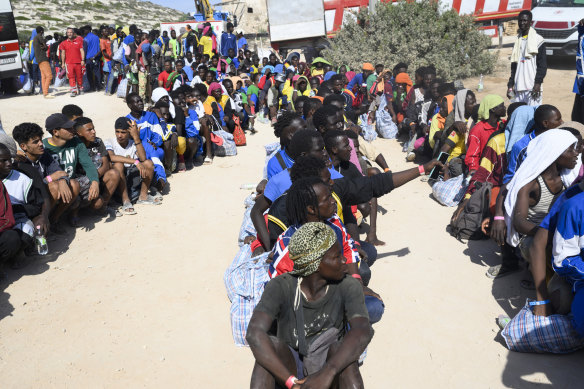 Migrants sit outside the Lampedusa’s migrant reception centre, Sicily, last week.