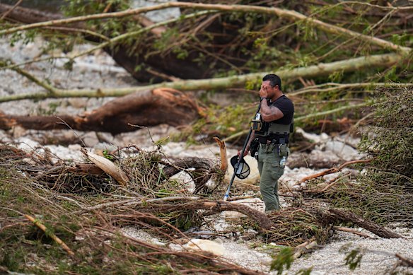 A sheriff’s deputy pauses while combing through the banks of the Guadalupe River near Camp Mystic.