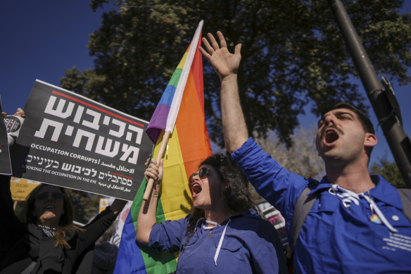 Demonstrators, waving a rainbow flag and a sign that reads