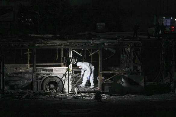 An Israeli police officer inspects the scene of one of a series of bus explosions in what authorities said appeared to be a militant attack in Bat Yam, central Israel, Thursday, Feb. 20, 2025.