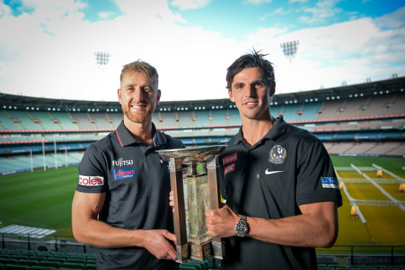 Essendon captain Dyson Heppell holding the Anzac trophy with Collingwood skipper Scott Pendlebury.