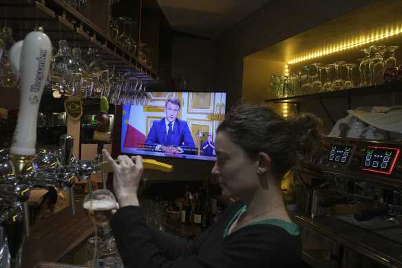 A bar TV shows the telecast of French President Emmanuel Macron’s address to the nation.