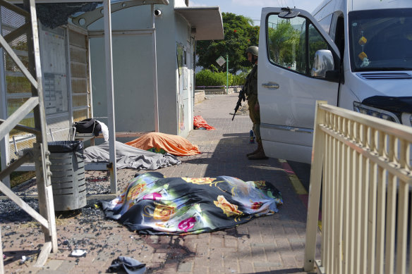 An Israeli soldier stands by the bodies of Israelis killed by Palestinian armed militants who entered from the Gaza Strip, in the southern Israeli city of Sderot.