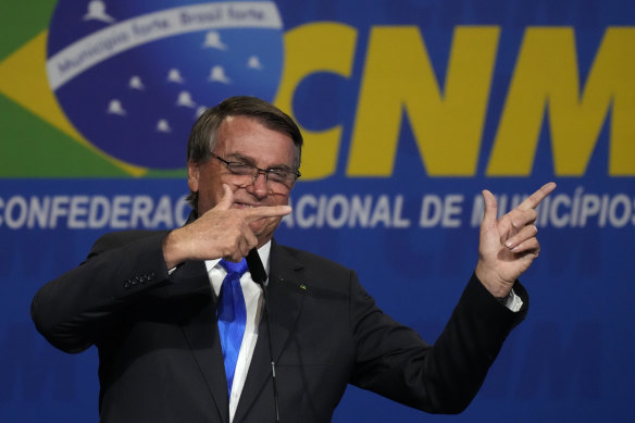 Brazilian President Jair Bolsonaro makes his signature gun-finger gesture at the opening of the national mayors’ meeting in Brasilia in April.