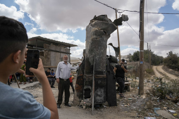 Palestinians take photos with the debris of an Iranian missile, intercepted by Israel, in the West Bank city of Hebron.