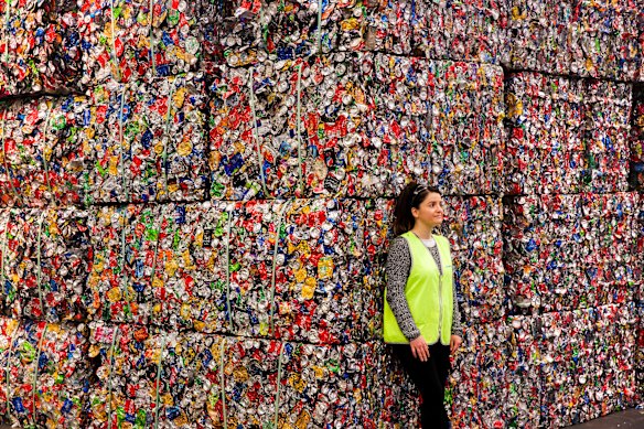 A Planet Ark worker stands by a mountain of recycled waste.