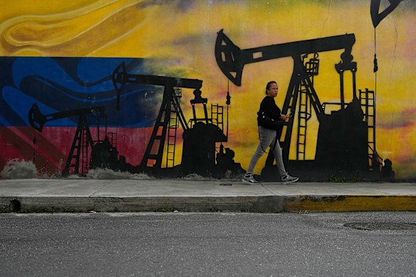 Um morador local passa por um mural representando bombas de petróleo e poços em Caracas, Venezuela, esta semana.