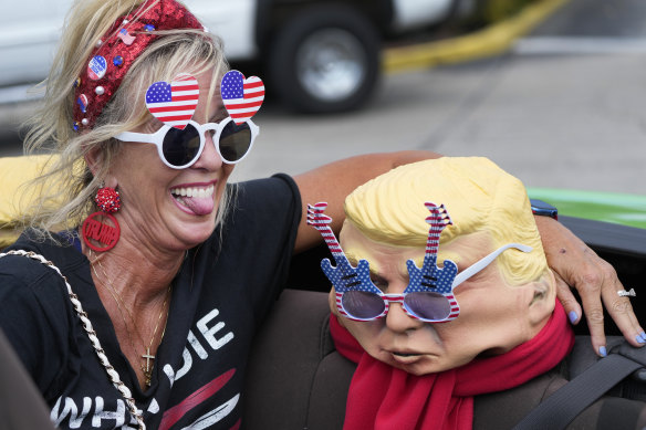 Michelle Lilly, a supporter of former president Donald Trump, poses with a mask of the former US leader.