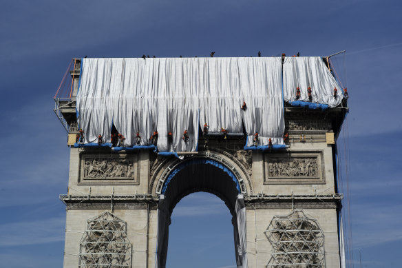 Workers unfurl the fabric from the top of the 50-metre high monument.