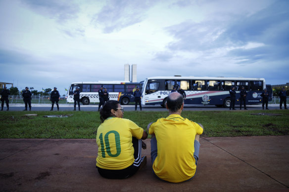 A couple of supporters of former president Jair Bolsonaro observe the movement of military police during an abortive protest in Brasilia on Wednesday.