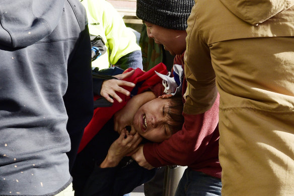 An anti-democracy protester grabs a man with a Taiwanese man around the neck at a rally in Sydney.
