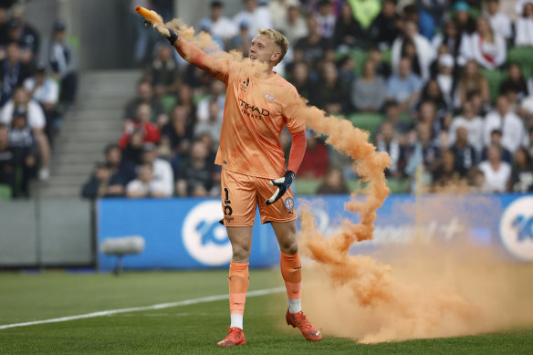 Melbourne City goalkeeper Tom Glover throws a flare from the field.