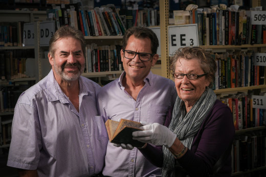 Greg Simpson of Brotherhood Books hands Les Robinson’s World War I diary to Les’ niece Jenny Robinson and great-nephew Michael Robinson.