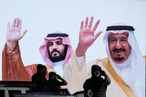 Saudi special forces salute in front of a screen displaying images Saudi King Salman, right, and Crown Prince Mohammed bin Salman.