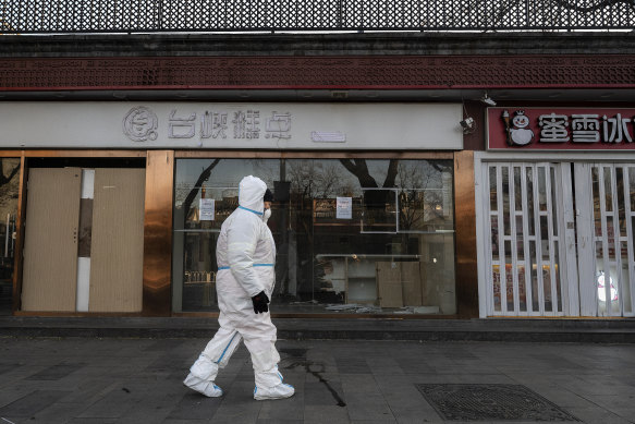 An epidemic control worker walks by closed shops in an area in lockdown in Beijing on December 1.