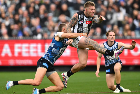 Jordan De Goey kicks while being tackled by Patrick Cripps.