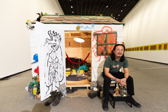 Jason Phu sits outside his bungalow artwork at ACCA. 