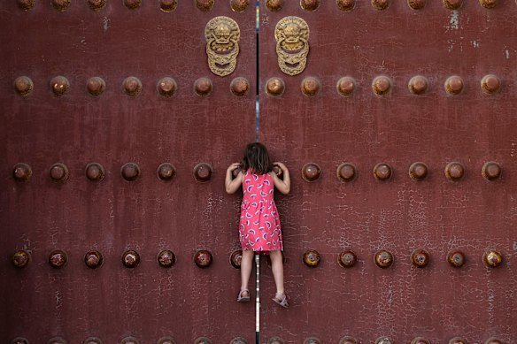 A girl climbs to look through a gap of the closed doors of the Hall of Prayer for Good Harvests at the Temple of Heaven in Beijing on Tuesday. In a rare occurrence, the popular historic site has been closed for the next three days in preparation for a tour by US President Donald Trump and Chinese President Xi Jinping on Thursday.  