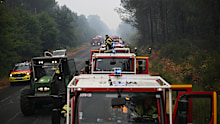 A firefighter stands on a truck on a road near Lacanau, southwestern France.