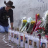 A man adjusts candles and flowers at a memorial to the victims of the deadly truck attack  in New Orleans.