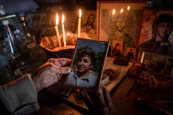 Effie holds a photo of her son Stephen at a household shrine.