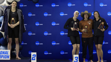 Lia Thomas (left) stands alone on the podium as the other placegetters pose for a group photo.
