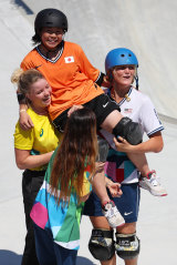 Misugu Okamoto of Team Japan is carried by Australian Poppy Olsen and American Bryce Wettstein after her fall at the skateboarding.