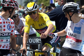 Mathieu Van Der Poel, wearing the overall leader’s yellow jersey, fist-bumps Tadej Pogacar, wearing the best young rider’s white jersey, with Ide Schelling in the best climber’s polka dot jersey, before the start of the sixth stage of the Tour de France on Thursday.