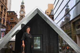 Caroline Pidcock, a cofounder of Architects Declare, looks into a double glazed and insulated room. It is part of the ice block challenge, testing whether ice melts faster in this house compared to another tiny house next to it built to current building standards. 